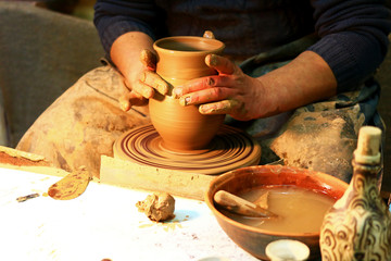 the potter in the workshop reveals the secrets of his work and begins to work the loam on the potter's wheel with his own hands to get a vessel, a close-up photo