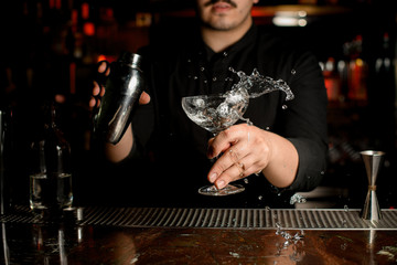 Bartender shaking alcohol in glass at counter