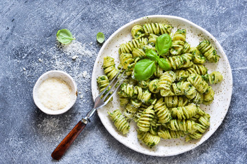 Pasta with pesto and parmesan on a concrete background. View from above.