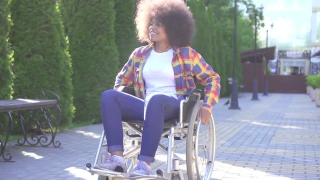 portrait of a positive smiling young African American woman disabled in a wheelchair on the street