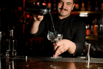 Bartender pouring an alcohol from shaker to glass