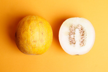 Fresh ripe melon on orange background. A piece of melon cut in half. flat laу