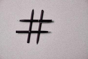 Fototapeta na wymiar Blogging, blog and blogger or social media concept: pens and hashtag symbol on grey background. Flat lay