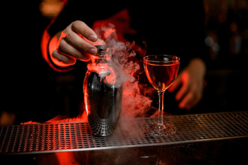 Close-up of steaming shaker and cocktail on counter