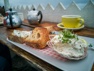 Mackerel pate on a plate with a cup of tea and pot 