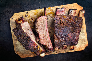 Barbecue chuck beef ribs with hot rub as top view sliced on a wooden cutting board - obrazy, fototapety, plakaty