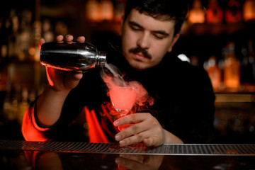 Bartender making steamy alcohol cocktail with shaker