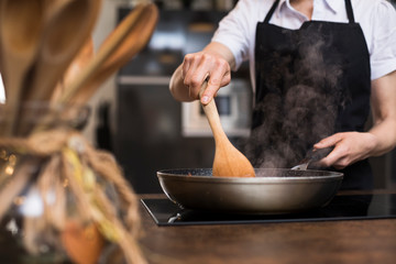 Close-up of woman cooking in kitchen using a pan