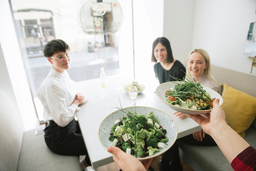 Waiter serving salad to friends in a restaurant