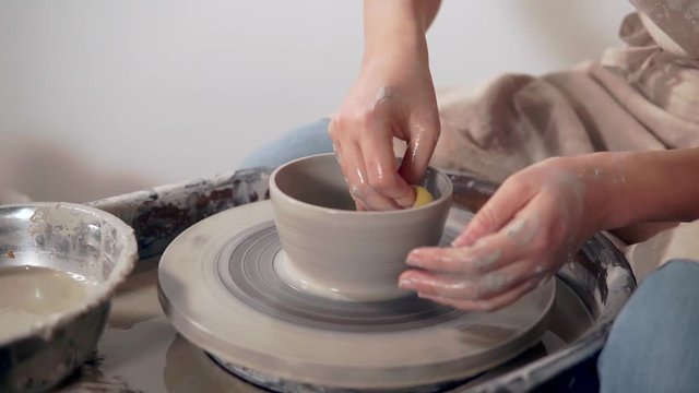 Sculpter making clay vase in studio.