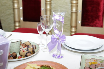 table setting for a wedding, crystal glass decorated with beads with rhinestones and satin ribbons, glasses, plates, plates of food. Luxury design.