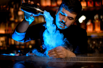 Bartender uses shaker to prepare an alcohol drink