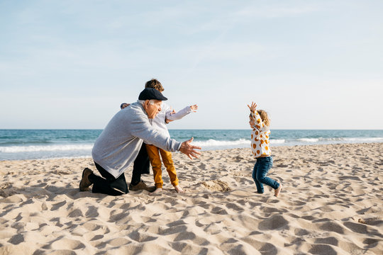 Grandfather playing with his grandchildren on the beach in spring