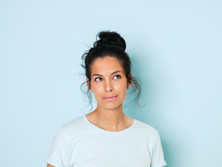 Portrait of young woman with black hair, light blue background