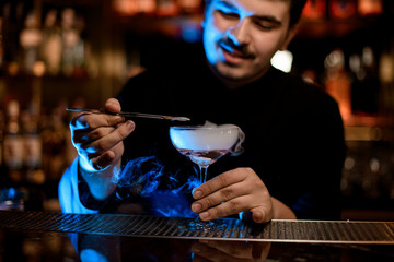 Bartender adding lemon slice in alcohol cocktail