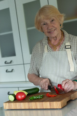 Senior or older woman cooking salad in kitchen. Healthy food concept. Healthy lifestyle. Grandma prepares a healthy meal for her grandchildren.