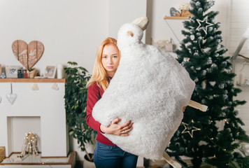 Funny female posing in christmas interior studio with decorative sheep in her hands.