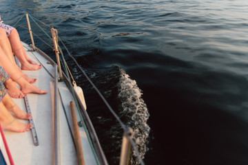 Obraz premium Many female legs on a white yacht. Bachelorette party on the yacht, dissecting the waves.