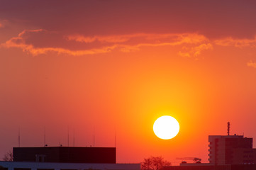 Cityscape and sunset with silhouettes of houses.