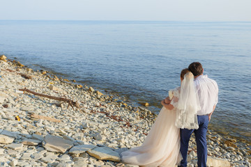 Bride and groom are hugging and looking at the sea