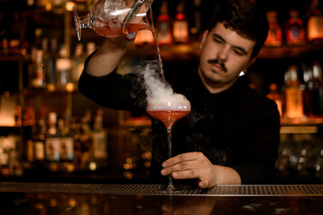 Bartender using strainer to prepare an alcohol drink