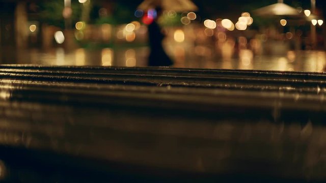 Rainy night in Barcelona. Drops of water on metallic fence. Light and colours on a background. Medieval European city night. People going on the background. Wet reflections and blurred night images