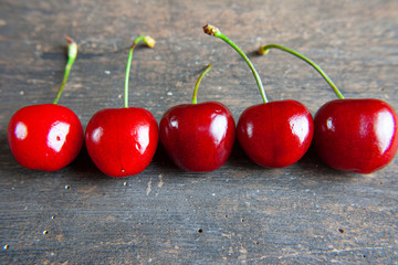 Soczyste, dojrzałe czereśnie na tle szarej, zniszczonej deski © Monika