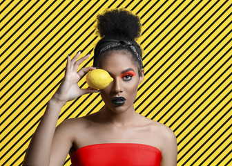 Beautiful attractive young woman with creative make-up and lemon near the eye
