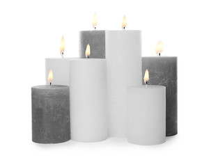 Many alight wax candles on white background