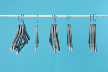Metal rack with clothes hangers on color background
