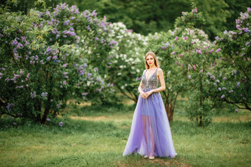 Obraz na płótnie Canvas beautiful young happy girl in an incredible dress resting outdoors,woman walking in the park amid blooming lilacs