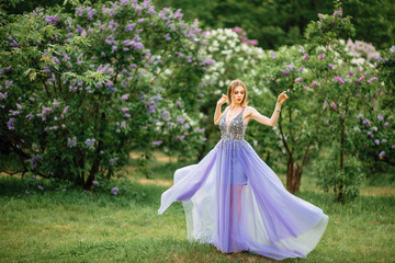 Obraz na płótnie Canvas beautiful young happy girl in an incredible dress resting outdoors,woman walking in the park amid blooming lilacs