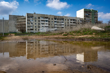 Fototapeta na wymiar Residential building in Elista is reflected in the spring puddle. Russian cities. Travels in Russia