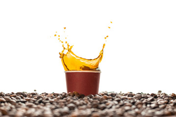 Coffee splash in brown disposable paper cup with coffee beans isolated on white. Concept: coffee...