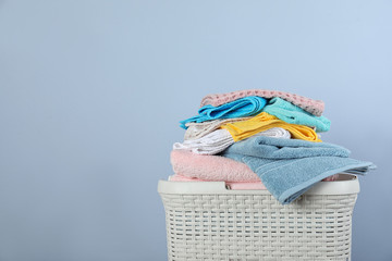 Laundry basket with clean towels on color background. Space for text