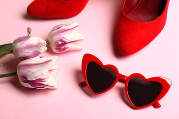 Heart shaped sunglasses, shoes and tulip flowers on color background