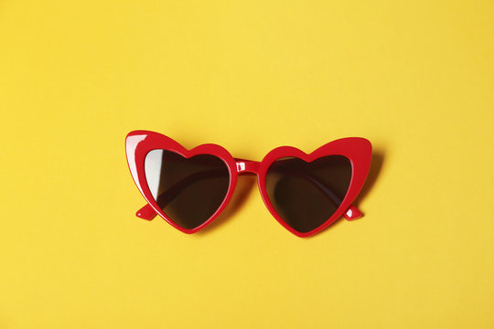 Stylish heart shaped glasses on color background, top view