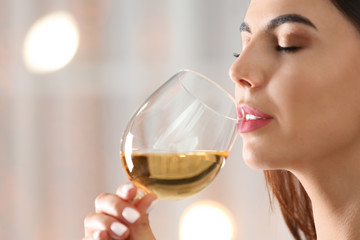 Beautiful young woman with glass of luxury white wine indoors, closeup view. Space for text