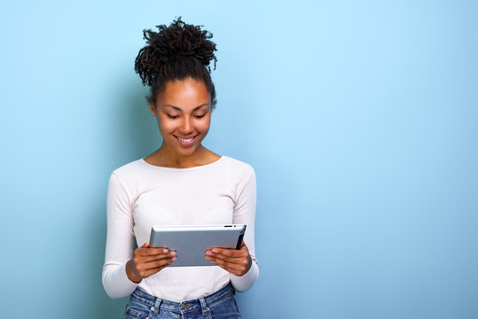 Smiling mulatto woman standing with ipad looking at the screen and happily smile