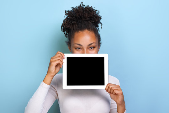 Mockup Image Of Black Empty Blank Screen Of Ipad In The Female Hand, Peeking From Behind Tablet Over Blue Background