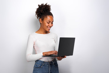 Portrait of girl holding laptop computer and ctyping looking at the screen