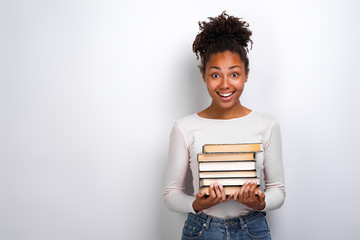 Portrait of an excited young girl holding books over white background. Back to school