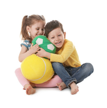 Cute little boy and girl with soft balls on white background