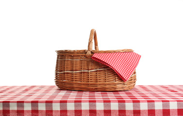 Empty picnic basket on checkered tablecloth against white background