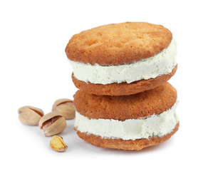 Sweet delicious ice cream cookie sandwiches and pistachios on white background