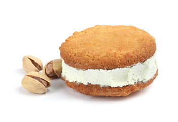 Sweet delicious ice cream cookie sandwich and pistachios on white background