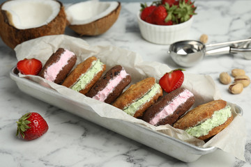 Different sweet delicious ice cream cookie sandwiches served on table