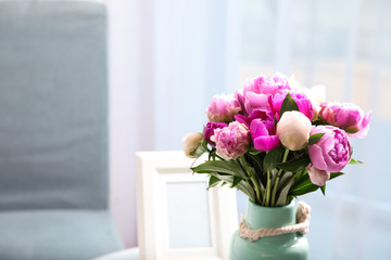Vase with bouquet of beautiful peonies in room, space for text