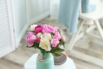 Vase with bouquet of beautiful peonies on table in room. Space for text