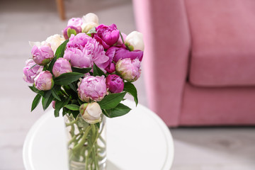 Bouquet of fresh peonies on table in room, space for text